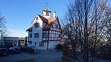 Restaurant Falkenburg, whose historical main building is a timber frame with a small turret.  The building stands on a slope south of the city of St. Gallen