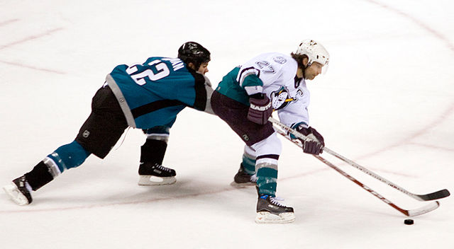 Scott Niedermayer battles for the puck with San Jose Sharks' Scott Hannan in a game during the 2005–06 season; signed in the 2005 off-season, he was l