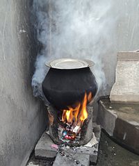A rural stove using biomass cakes, fuelwood and trash as cooking fuel. Surveys suggest over 100 million households in India use such stoves (chullahs) every day, 2-3 times a day. It is a major source of air pollution in India, and produces smoke and numerous indoor air pollutants at concentrations 5 times higher than coal. Clean burning fuels and electricity are unavailable in rural parts and small towns of India because of limited and deteriorating infrastructure. The rural stove,smoky,pollution,TamilNadu-230.jpeg