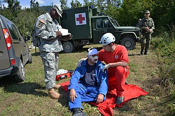 U.S. Army Sgt. 1st Class Ahmad Whitted, standing, an observer-controller, monitors the interaction between a role player and a Slovenian Civilian Protection agent Aug. 25, 2014, in Postojna, Slovenia, during 140825-A-BD830-003.jpg