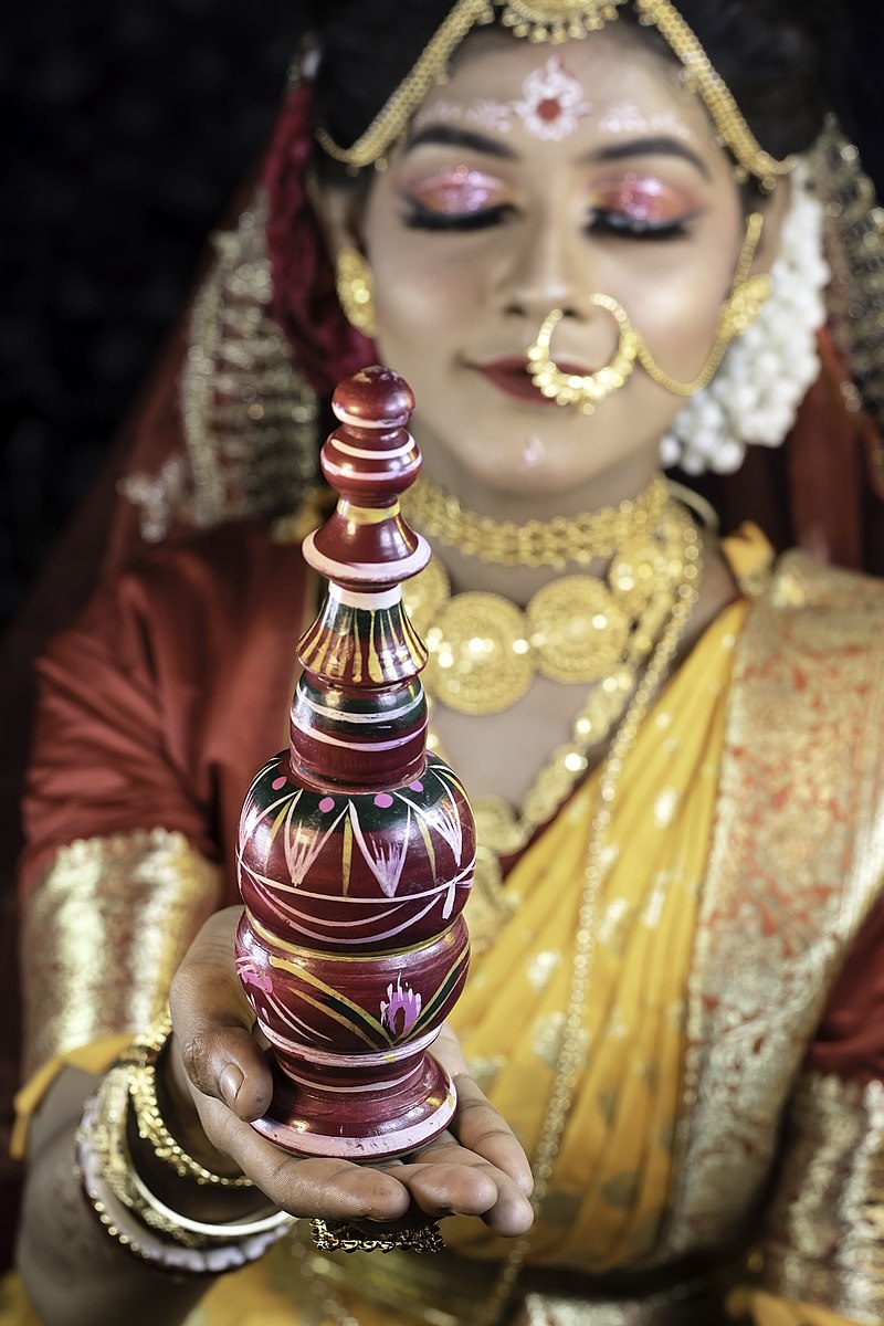 https://upload.wikimedia.org/wikipedia/commons/thumb/9/94/Bengalis_have_this_tradition_were_their_wedding_Bride_carries_the_%22Gachh_Kouto%22_is_a_small_pot_rack_on_the_wedding_Day.jpg/800px-Bengalis_have_this_tradition_were_their_wedding_Bride_carries_the_%22Gachh_Kouto%22_is_a_small_pot_rack_on_the_wedding_Day.jpg