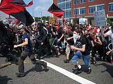 Black bloc protesters parading anarcho-communism imagery such as the motto "No War but the Class War" Black bloc at RNC running.jpg