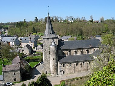 The houses of a small town, surrounded by green hillsides, are dominated by a huge church with a large square tower and a spire like a witch's hat.