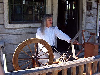 Knott's Berry Farm spinner Charlene Parker demonstrates how to transfer thread or yard from a spinning wheel (on left) to a spinner's weasel (on right). Charlene Parker demonstrating how thread or yarn is tranferred from a spinning wheel to a clock reel..jpg