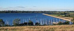 V popředí zakotvilo jezero s rekreačním plavidlem