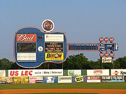 A view of the giant blue guitar-shaped scoreboard beyond the left-center field wall. Advertisements for local businesses adorn the guitar and the green outfield wall below.