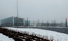 A photo of a glass panelled light rail station with the name "Kennedy" in bold white lettering on the side. The structure is mostly completed, but signage over the entrances has not yet been added.