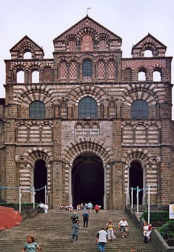 Uma fachada de igreja altamente ornamental construída em cursos alternados de pedra vermelha e branca.