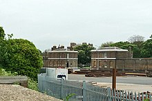 Main entrance in 2018: the old dockyard police station and police house (formerly linked by a colonnaded gateway, since demolished). North and South Gatehouses, Sheerness Dockyard (geograph 5777134).jpg