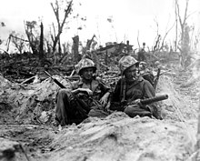 Marine Pfc. Douglas Lightheart (right) cradles his .30 caliber (7.62x63mm) M1919 Browning machine gun in his lap, while he and Pfc. Gerald Thursby Sr. take a cigarette break, during mopping up operations on Peleliu on September 15, 1944. Resting on Peleliu Island.jpg