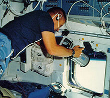 Overmyer aiming a camera out of an overhead window of Space Shuttle Challenger during the STS-51-B mission