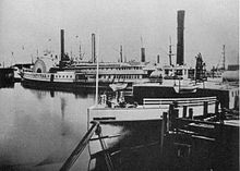 Contra Costa, in the foreground, was one of the earliest ferries built expressly for trans-bay service. Capital, in the background, formerly a Sacramento River steamboat, served the route from 1876 to 1896. Both were built by John Gunder North. Sidewheelers Capital and Contra Costa at Davis Street Landing.jpg