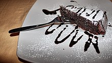 A dark brown cake, sliced to reveal a heavy, moist interior
