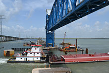 A barge passing under the new lift span on the railroad causeway, with the 2008-opened new causeway for road vehicles visible at left. Tug and barge passing under new lift span of Galveston Causeway rail line, viewed from below bridge, Aug. 2012.jpg