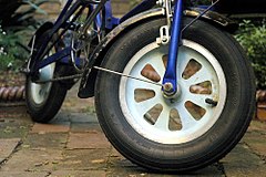 Cast alloy wheel on a folding bicycle, with a pneumatic tire.