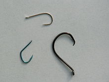 (Clockwise from top) A standard J-hook with straight eye, a circle hook with down-turned (outward angled) eye, and an eyeless Japanese Tenkara hook with a spade end. FishHooks.JPG
