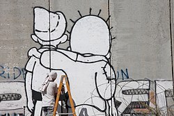 Graffiti as peace activism: The Peace Kids on the Israeli West Bank barrier depicting Palestinian Handala and Israeli Srulik embracing one another. Graffiti of Peace in Bethlehem on Apartheid Wall by Street Artist Kis-Lev.jpg