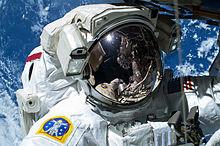 Barry "Butch" Wilmore conducting a spacewalk in 2015, with Earth visible in the background. Terry Virts accompanied Wilmore on this EVA; the inverted reflection of Virts is visible in the visor of Wilmore's EMU space suit. ISS-42 EVA-1 (a) Barry "Butch" Wilmore.jpg