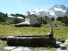 La fontaine et la chapelle Saint-Clair au hameau du Monal à Sainte-Foy-Tarentaise en Haute-Tarentaise, dans le parc de la Vanoise, en Savoie. En arrière plan, se dresse les faces est du Mont Turia sur la droite du massif et du Mont Pourri au centre (avec la Brèche Puiseux à son pied, côté sud), ainsi que le Dôme de la Sache sur la gauche.