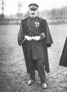 Photo en noir et blanc d'un homme à moustache, en uniforme de lieutenant de marine française, dans une prairie.