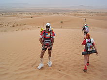 Coureurs dans un paysage de dunes de sables.