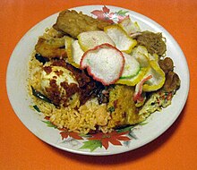 Traditional Betawi nasi uduk, mixing all the side dishes on the nasi uduk plate, such as egg, tempeh, sambal, bihun goreng, and krupuk Nasi Uduk Betawi.jpg