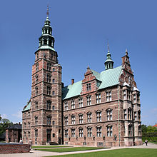 Kasteel met torentjes en torenspitsen en ommuurde omheining, op het puntje van een smal schiereiland.