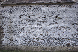 Muro di pietra cieco forato con piccoli fori quadrati.