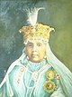 A woman wearing the robes and insignia of the Order of the Star of India; she sports an elaborately chased gold headdress, looped at the front with pearls, and surmounted by a white plume (see the details on the Royal Collection site)