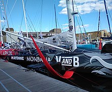 Milieu noir du bateau amarré au ponton. On voit le corps du dragon gris. Foil rouge, bas du mât blanc et un outrigger blanc.