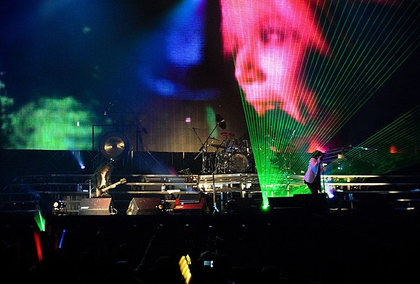 X Japan performing in 2009 with an image of Hide in the background. Despite his death, they still consider him a member of the band.