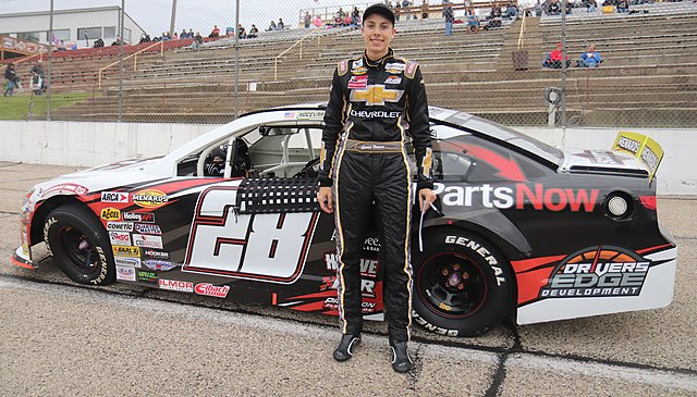 Hocevar standing next to his No. 28 car in 2019 before the race at Madison