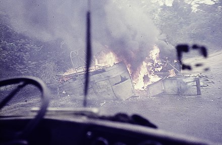 Burning car wrecks of a van and a tank truck seen through the windshield in Southern Nigeria, 1970 - 1973.