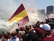 Detroit City FC supporters with the city's skyline behind them during a match at Cass Tech in 2013. Detroit City FC supporters stands.JPG