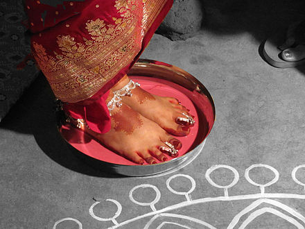 A Bengali Hindu bodhu boron ceremony welcoming the newlywed bride to her new home, with the feet dipped in a mixture of milk and alta.