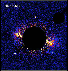 Cirkumstelární disk kolem hvězdy HD 139664 na snímku Hubblova vesmírného dalekohledu. Hvězda samotná je skryta za clonou koronografu.