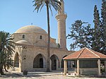 Mosquée en pierre, un minaret et un sanctuaire devant.