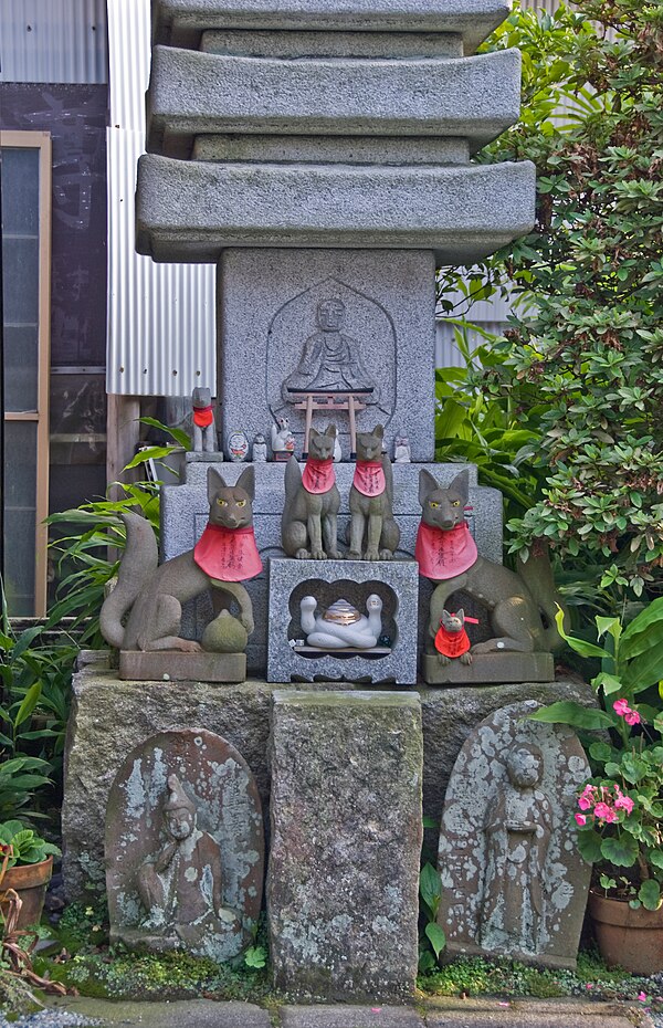 Foxes sacred to Shinto kami Inari, a torii, a Buddhist stone pagoda, and Buddhist figures together at Jōgyō-ji, Kamakura.