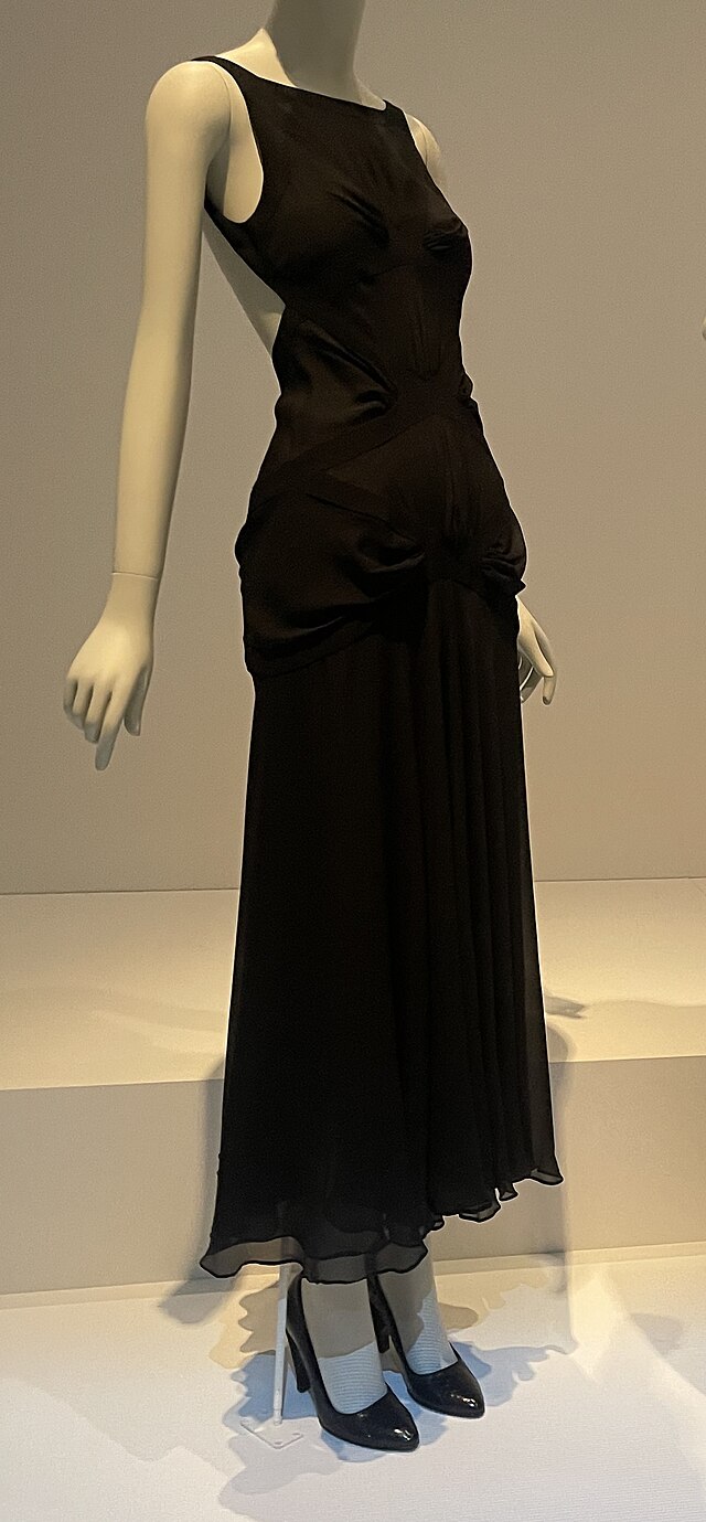 Floor-length sleeveless black dress with black high-heeled shoes, presented on a mannequin