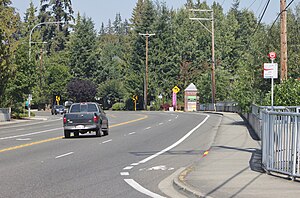 A five-lane road with a single truck, a bicycle lane, and a bus stop sign placed on its sidewalk