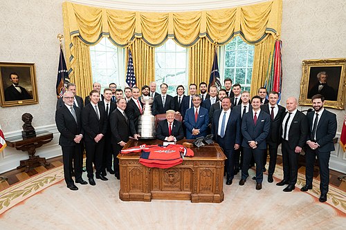 נשיא ארצות הברית, דונלד טראמפ, עם קומישנר ה-NHL גארי בטמן (שלישי משמאל בשורה הקדמית), אנשי ושחקני הקפיטלס, בקבלת פנים בחדר הסגלגל לרגל הזכייה בגביע סטנלי ב-2018