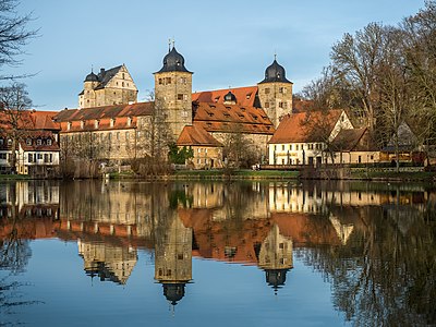 The castle reflects on the surface of the mill pond.