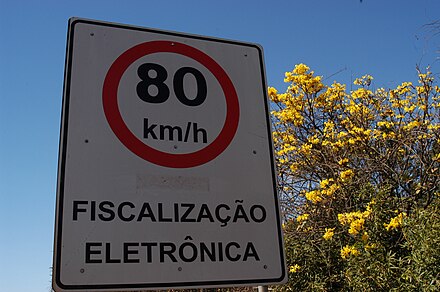 A street sign indicating that the speed limit is 80 km/h. This specific one means that there are speed guns some 400 m ahead.