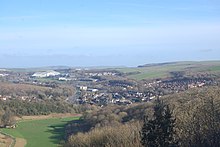 The housing of Moulsecoomb spreads to the east of Lewes Road, visible centre-left. Beyond is Falmer Stadium; Wild Park is bottom left. View of North Moulsecoomb and Amex Stadium from Hollingbury Hill, Brighton (February 2020).JPG