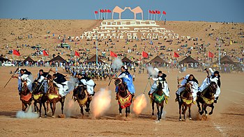 رجالٌ من قبائل صحراويَّة يؤدّون عرض فانتازيا خلال موسم طانطان في طانطان، بالمغرب