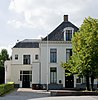 Groot huis (midden 19e eeuw) met witgepleisterde lijstgevel