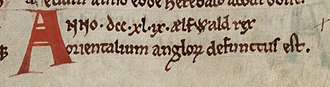 Primer plano de un manuscrito: dos líneas de texto en tinta negra precedidas por una A mayúscula en rojo