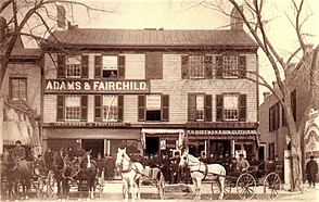 1886 photograph featuring the Arnold's Tavern storefront. "E. A. Van Fleet, H. H. Fairchild, and F. H. Fairchild are identified as standing behind [the carriages] on the left" while the Hoffmans stand on the right. Images of America: Morristown does not specify which carriages. Arnold's Tavern as Adams & Fairchild and P. F. Hoffman & Son Clothiers 2.jpg