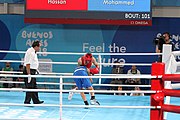 Deutsch: Boxen bei den Olympischen Jugendspielen 2018 Tag 12, 18. Oktober 2018 - Kampf um Bronze im Leichten Weltergewicht Jungen – Hassan Azim (Großbritannien, rot) schlägt Mohammed Boulaouja (Marokko, blau) RSC; Ringrichter ist Wulfren Olivares Peréz (Kolumbien). English: Boxing at the 2018 Summer Youth Olympics on 18 October 2018 – Bronze Medail Match Light Welterweight Boys - Hassan Azim (Great Britain, red) beats Mohammed Boulaouja (Morocco, blue) RSC; Referee is Wulfren Olivares Peréz (Columbia). Español: Boxeo en los Juegos Olímpicos Juveniles de Verano de 2018 en 18 de octubre de 2018 - Medalla de bronce de los hombres ligeros de peso welter: Hassan Azim (Gran Bretaña, rojo) vence a Mohammed Boulaouja (Marruecos, azul) RSC; El árbitro es Wulfren Olivares Peréz (Colombia).