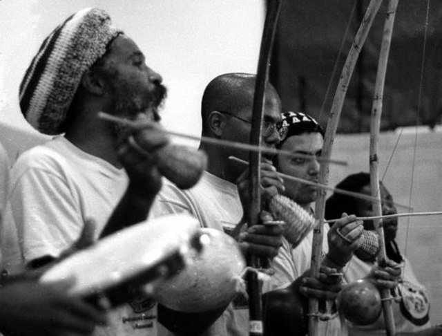 Three berimbau players playing the rhythm for a capoeira in Baltimore, MA, featuring Mestre Cobra Mansa